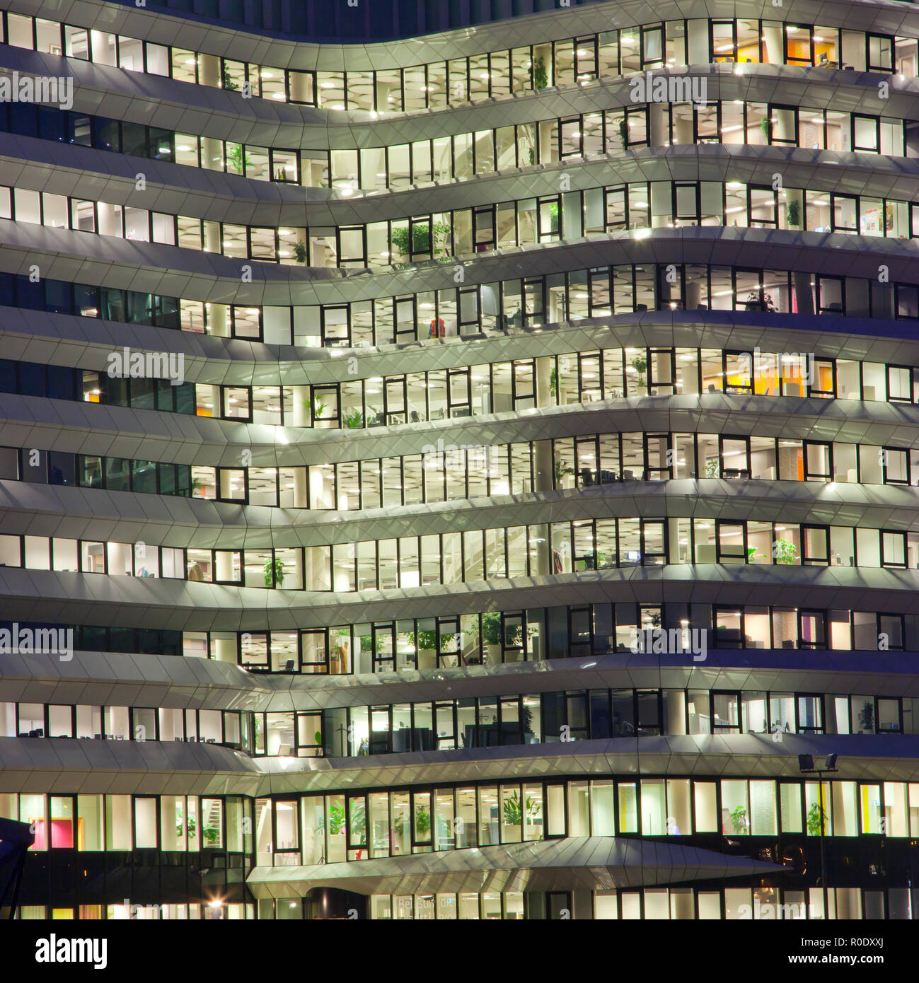 Office Building Lights at Night in the City with People at Work Stock