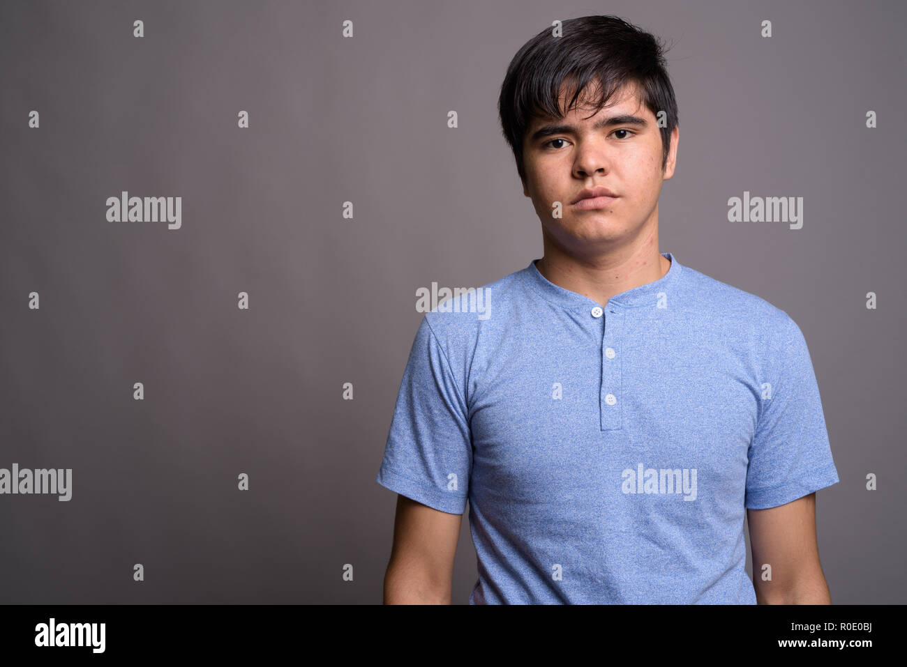Young Asian teenage boy wearing blue shirt against gray backgrou Stock ...