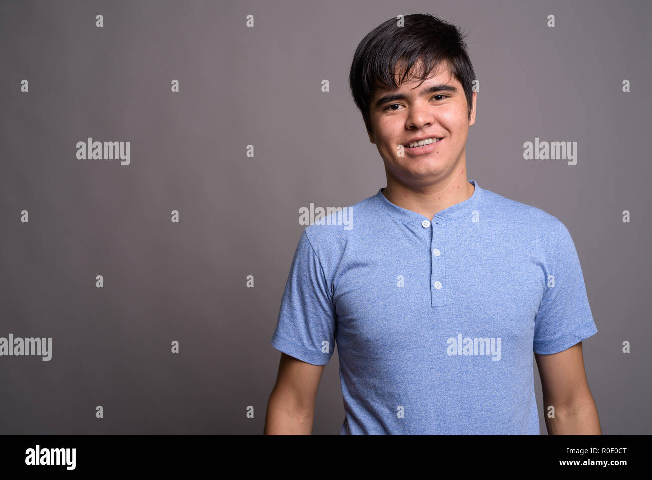 Young Asian teenage boy wearing blue shirt against gray backgrou Stock ...