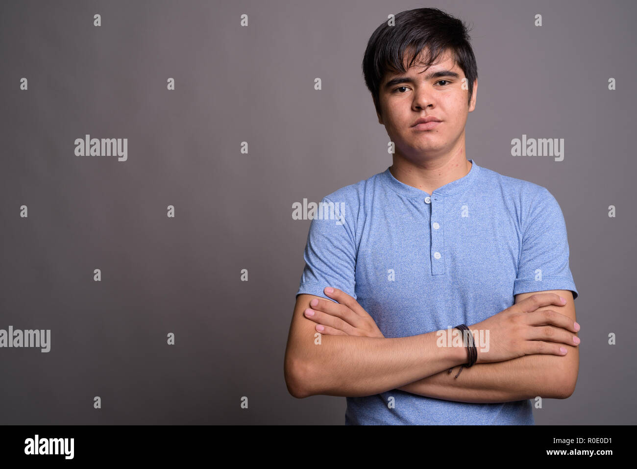 Young Asian teenage boy wearing blue shirt against gray backgrou Stock ...