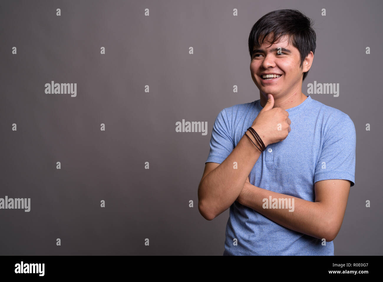 Young Asian teenage boy wearing blue shirt against gray backgrou Stock ...