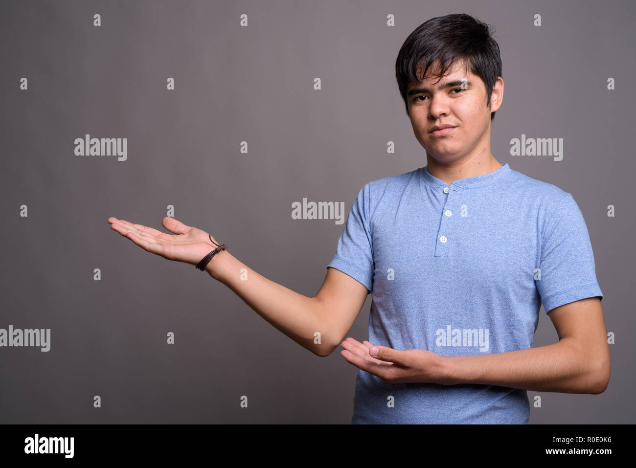 Young Asian teenage boy wearing blue shirt against gray backgrou Stock ...