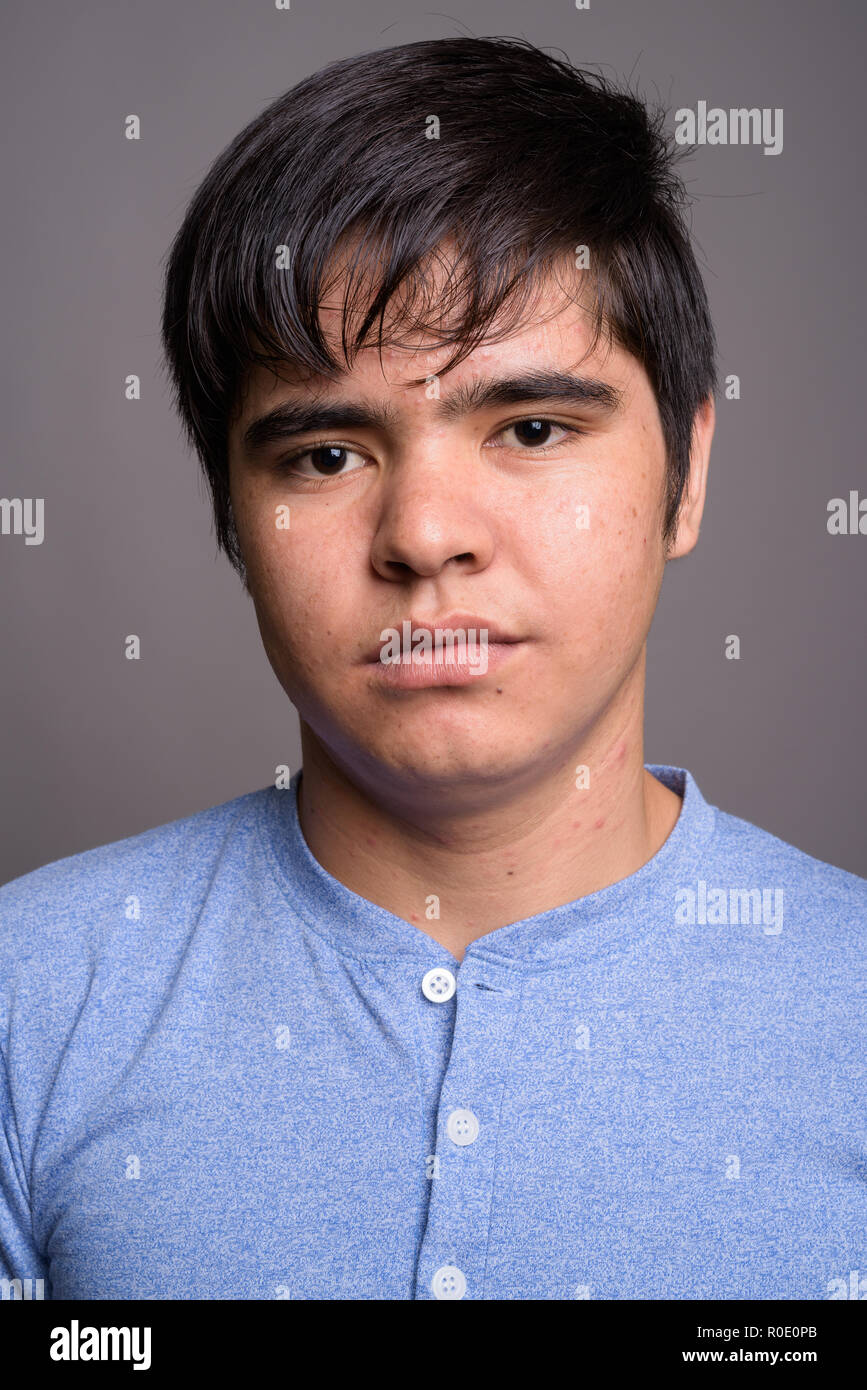 Young Asian teenage boy wearing blue shirt against gray backgrou Stock ...