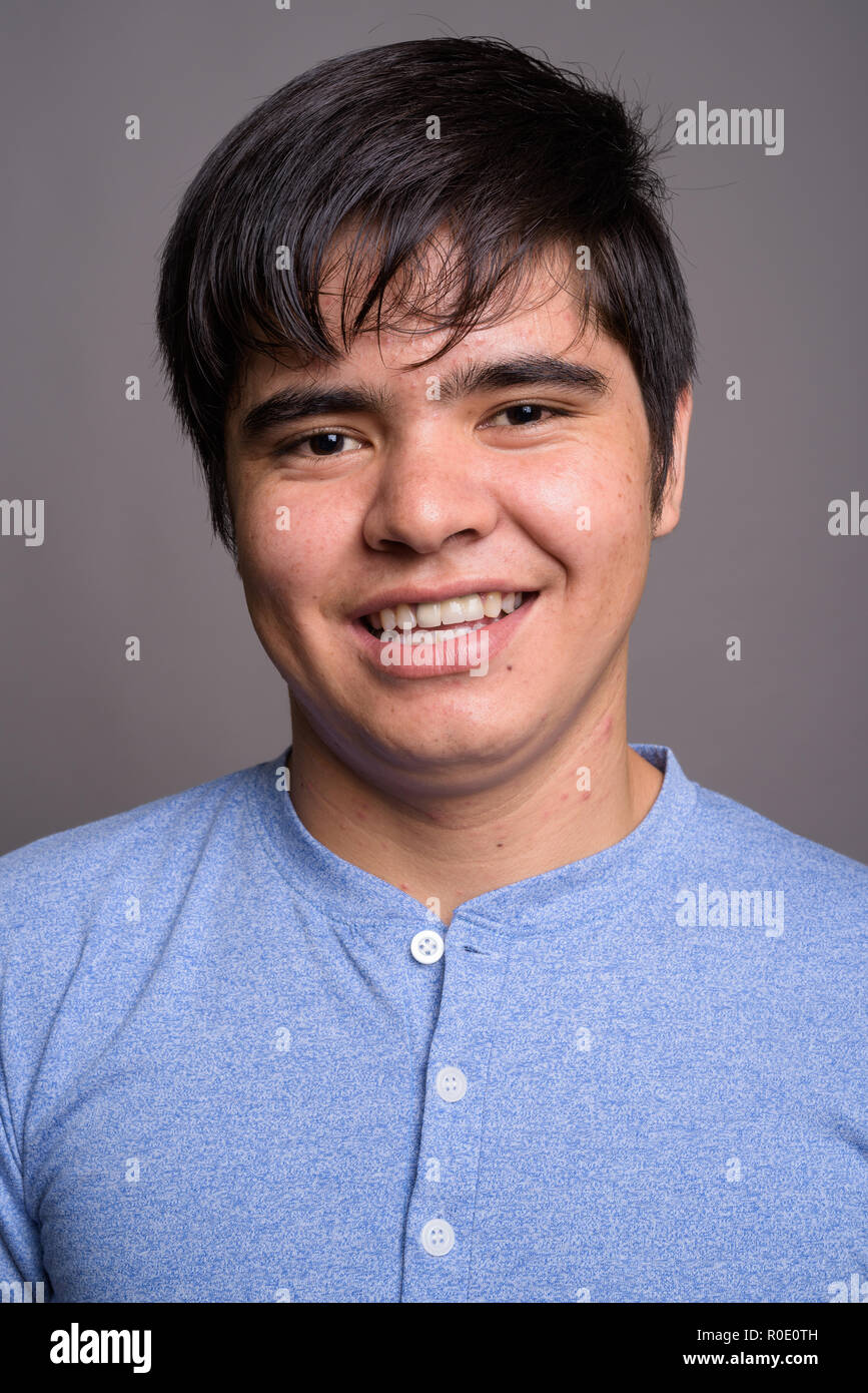 Young Asian teenage boy wearing blue shirt against gray backgrou Stock ...