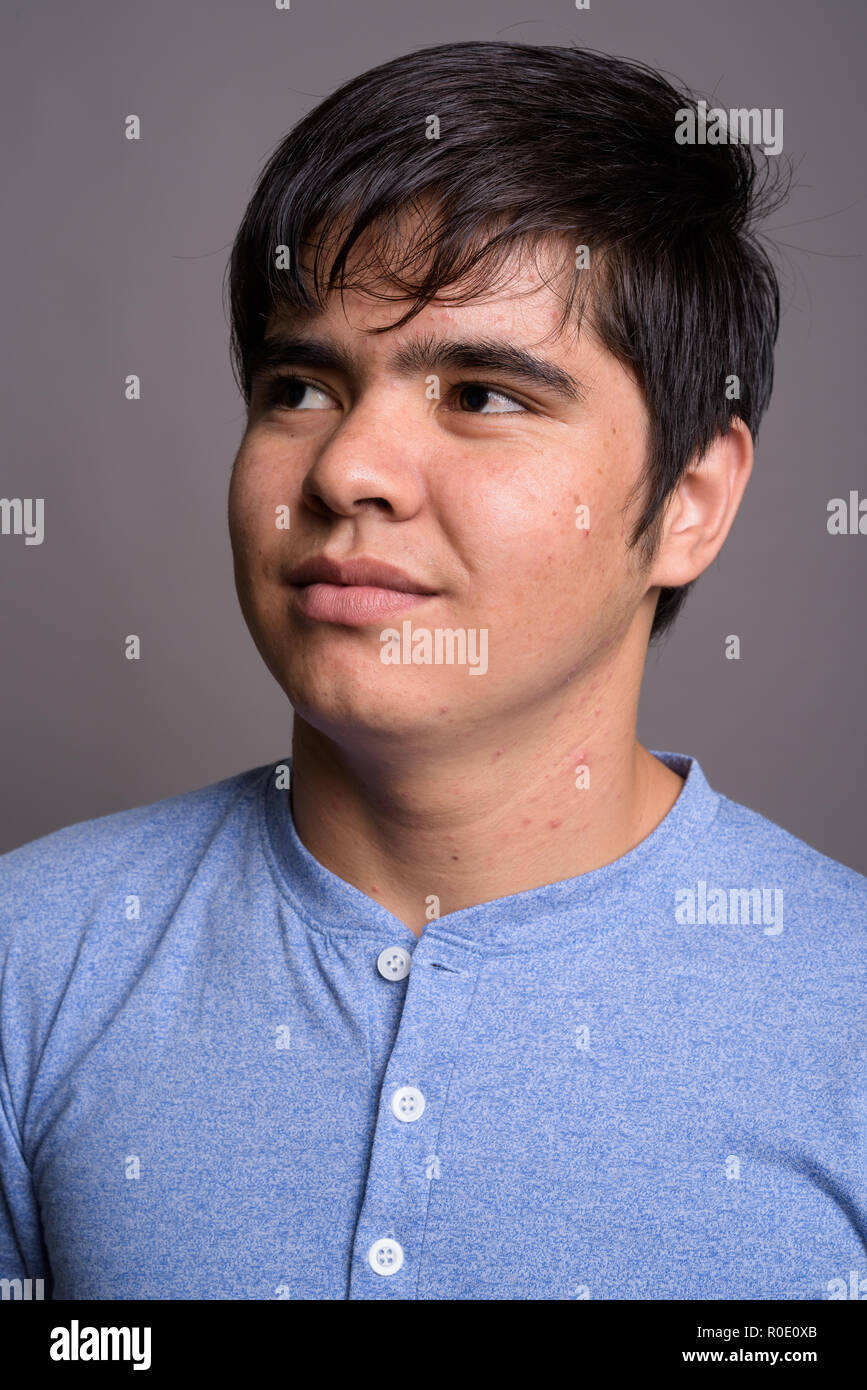 Young Asian teenage boy wearing blue shirt against gray backgrou Stock ...