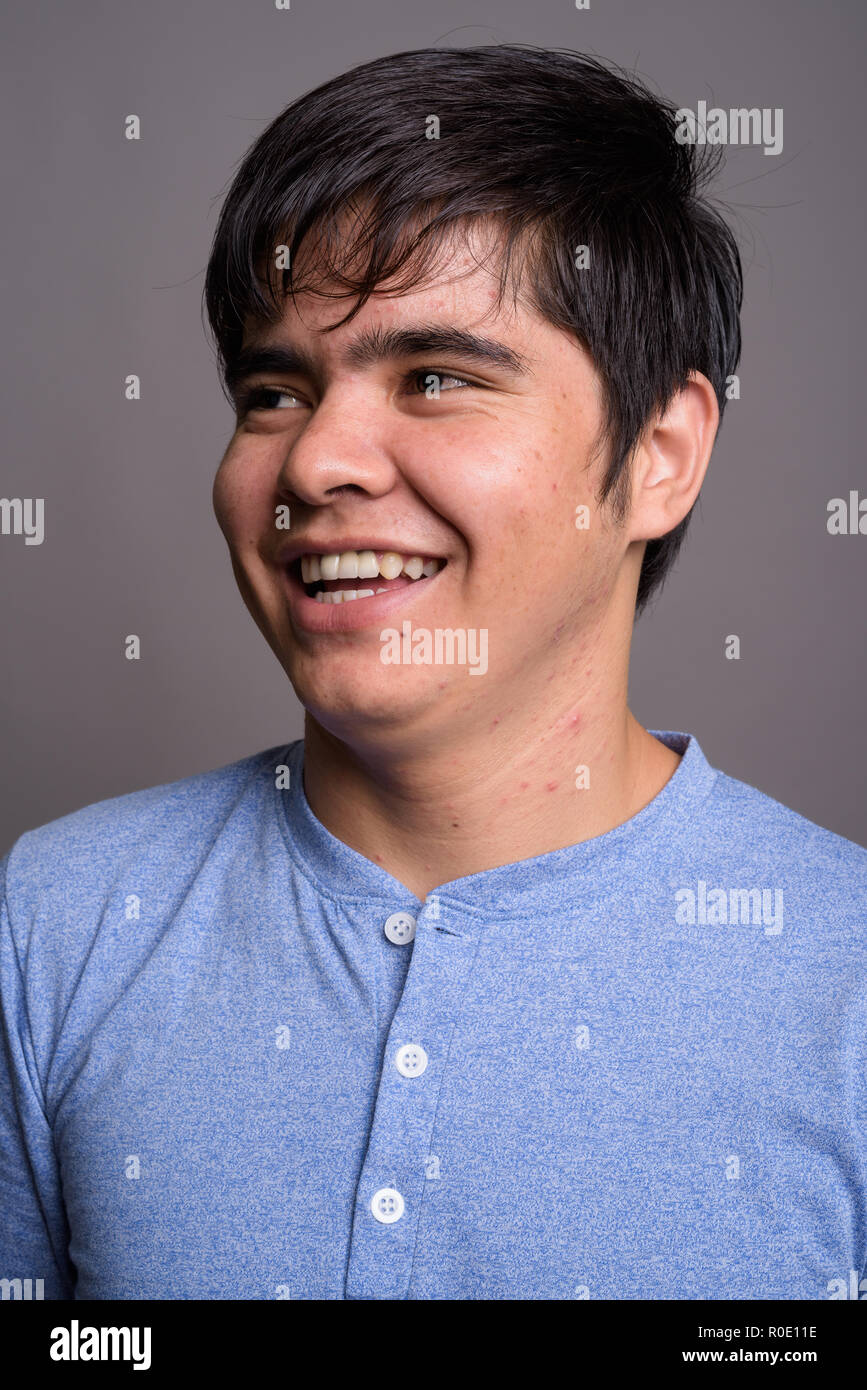Young Asian teenage boy wearing blue shirt against gray backgrou Stock ...