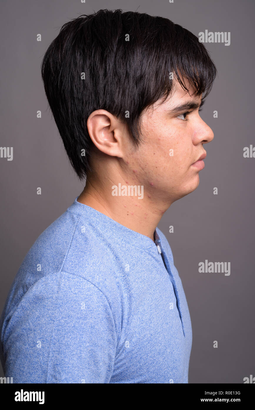 Young Asian teenage boy wearing blue shirt against gray backgrou Stock ...