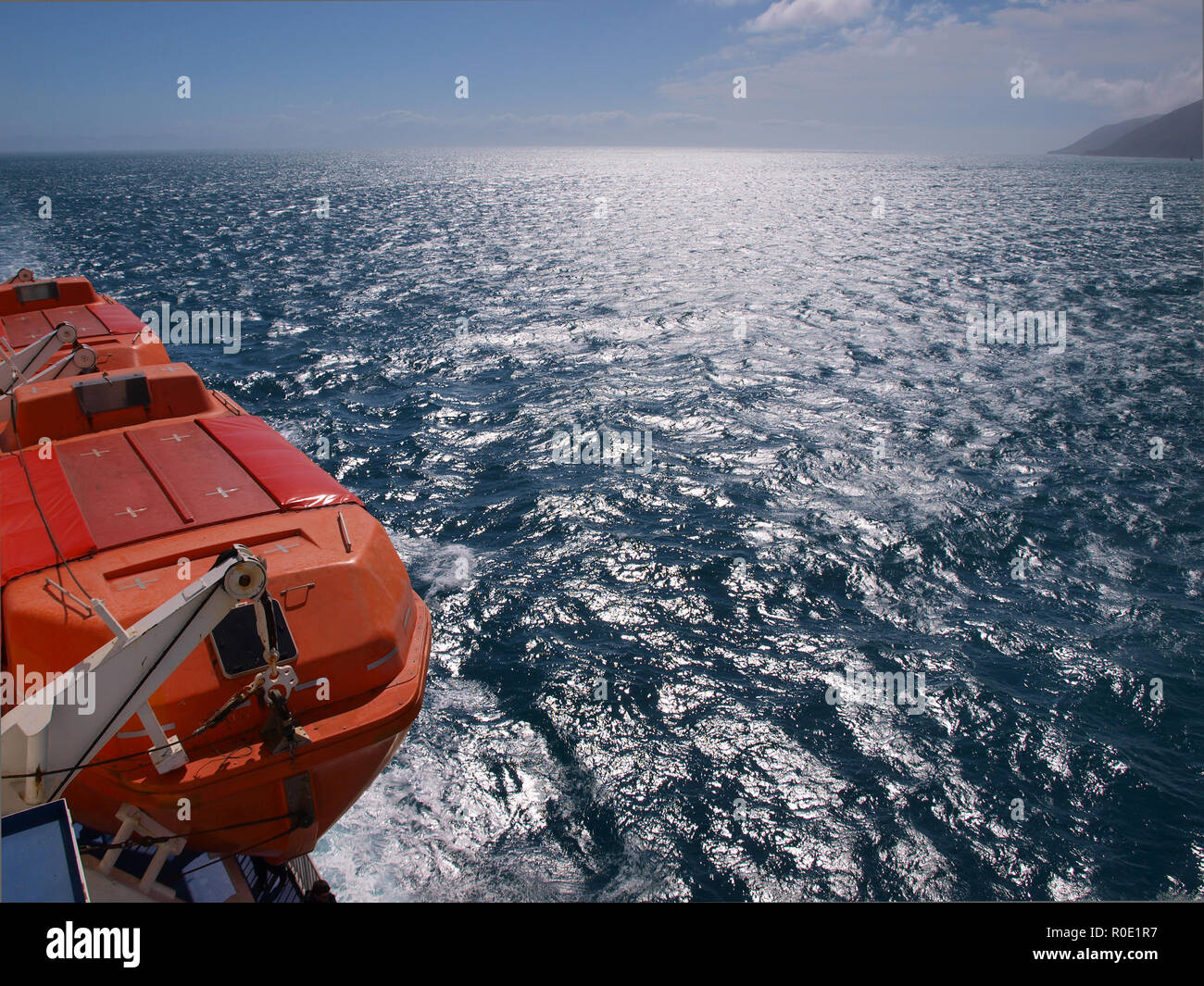a lifeboat on a the side of a ferry above a deep blue sea Stock Photo