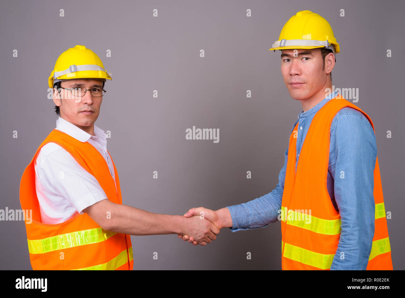 Two young Asian men construction worker together against gray ba Stock  Photo - Alamy