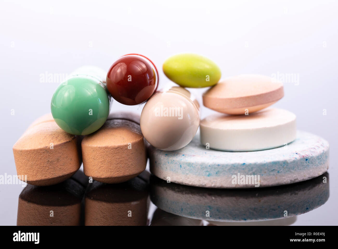Multiple capsules and pills isolated on black reflective surface