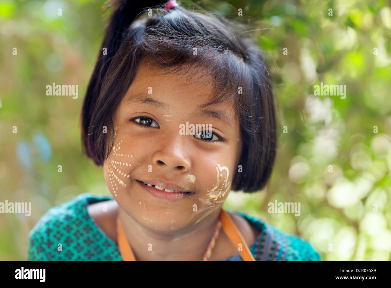 SANGHLABURI, THAILAND, JANUARY 24, 2016 : A Thai little girl with Burmese Thanaka cosmetic powder is posing near a temple in Sanghlaburi, Thailand Stock Photo