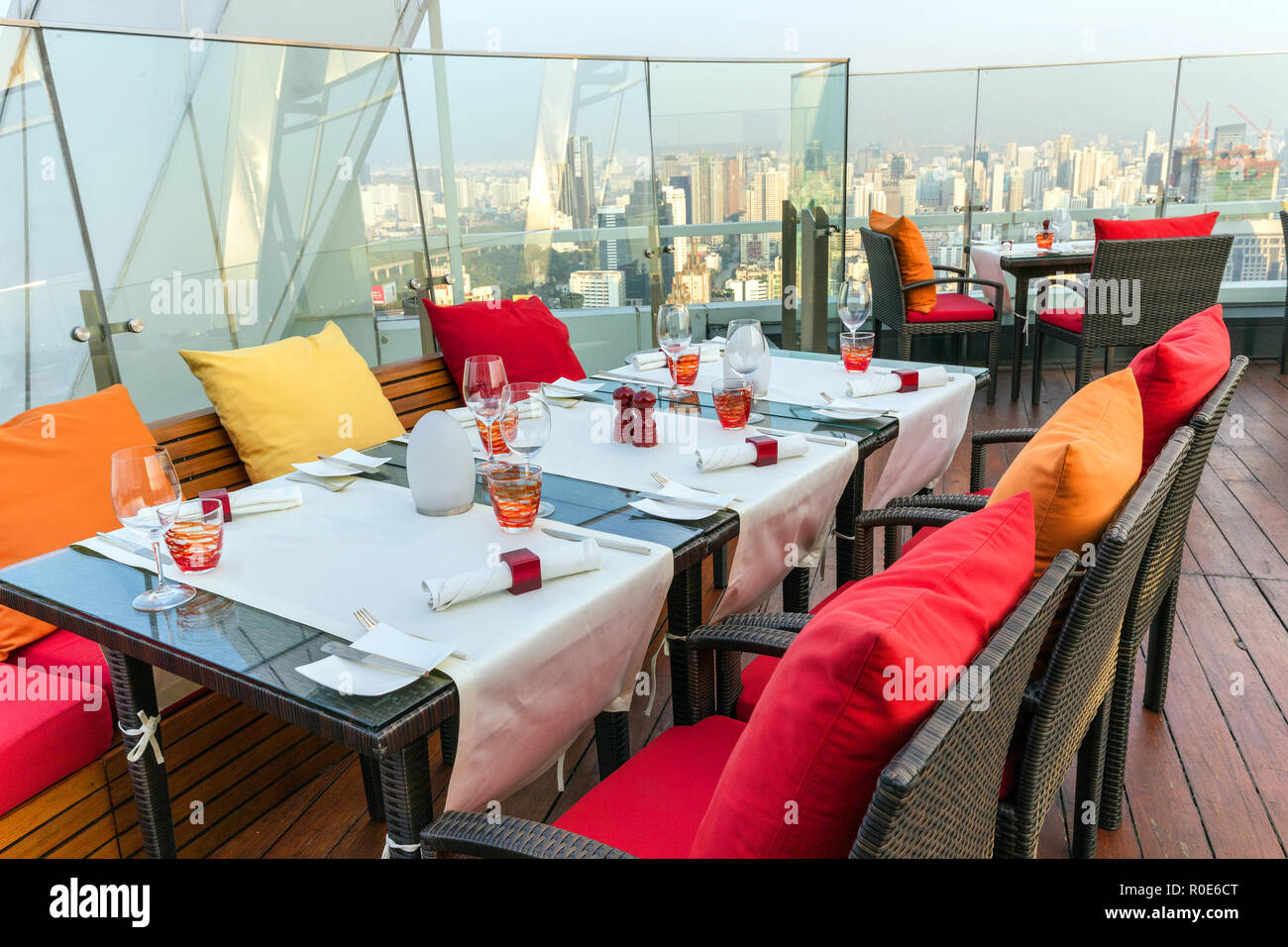 BANGKOK, THAILAND, JANUARY 14, 2015: Restaurant table with view on the cityscape at the Red Sky Rooftop of the Centara hotel in Bangkok, Thailand. Stock Photo