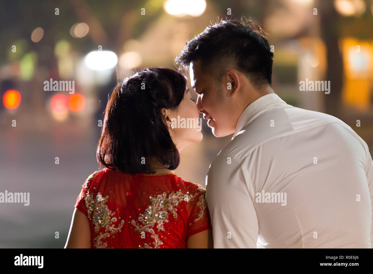 HANOI, VIETNAM, DECEMBER 15, 2014: Two young married people are exchanging a love kiss in evening at the city center's Hoan Kiem lake in Hanoi city, V Stock Photo