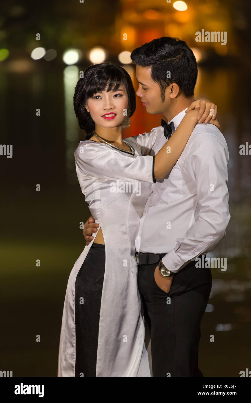 HANOI, VIETNAM, DECEMBER 15, 2014 : Two young married people are posing in evening at the city center's Hoan Kiem lake in Hanoi city, Vietnam. Stock Photo