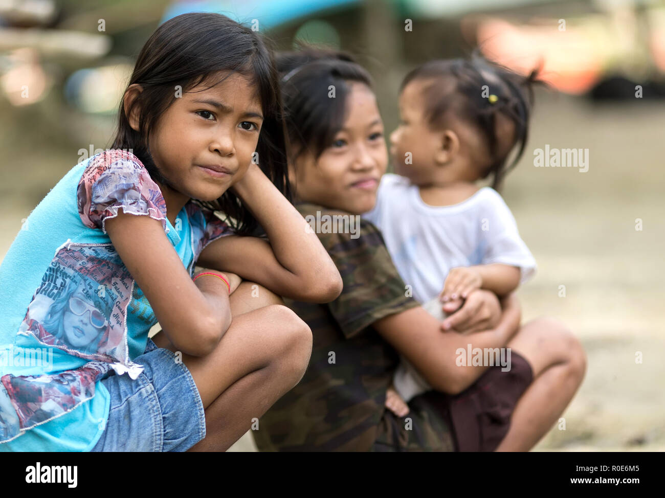 EL NIDO, PHILIPPINES, JANUARY 11 : Kids of a poor filipino family are sitting outdoor, one is holding her  young sister, El Nido, Philippines, on janu Stock Photo