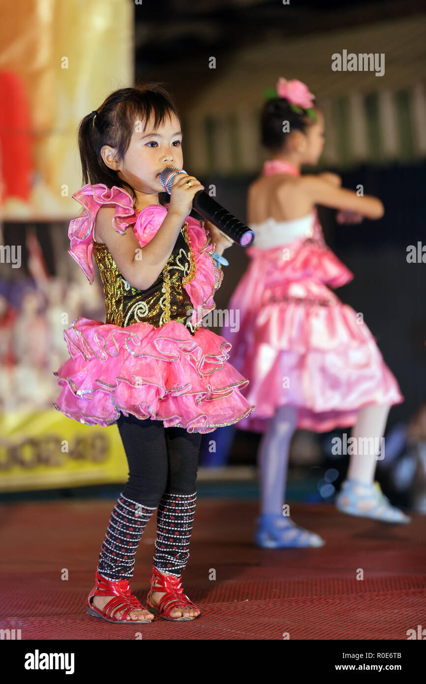 CHIANG MAI, THAILAND, FEBRUARY 26, 2012: Little girls are singing traditional Thai songs on stage during the night week-end market in Chiang Mai, Thai Stock Photo