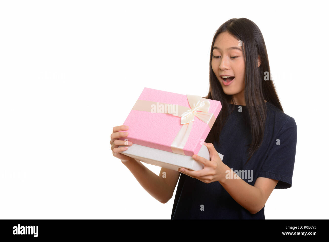 Surprised beautiful Asian teenage girl opening gift box Stock Photo