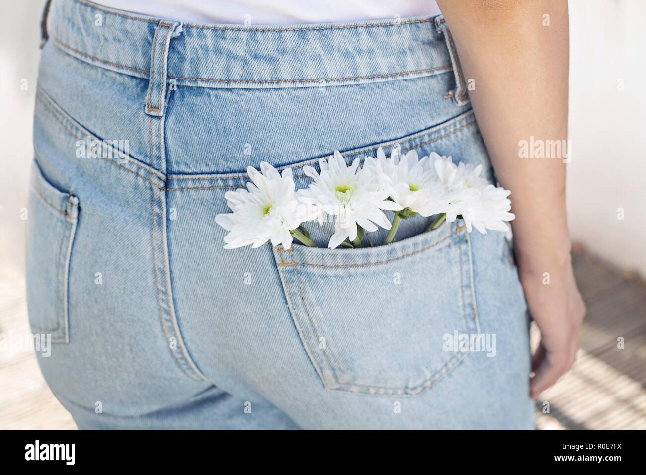 Woman with white flowers in back pocket of her jeans. Stock Photo