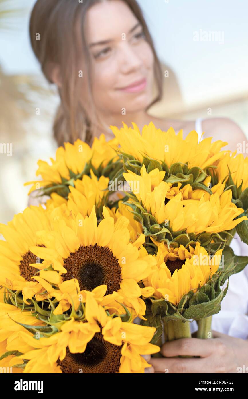 Young woman with sunflowers (Helianthus sp.). Stock Photo