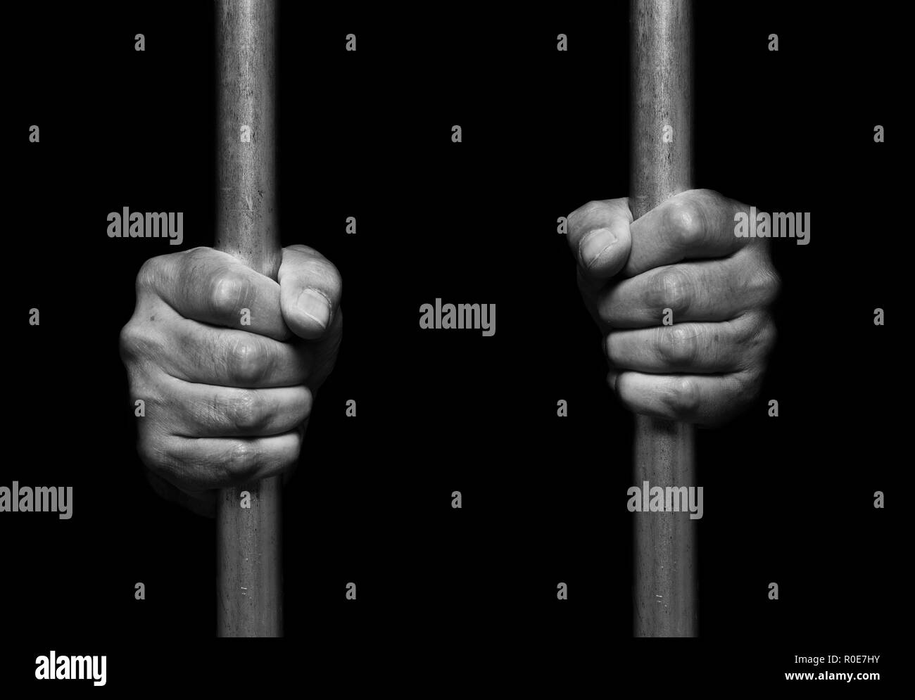 Person's hands holding prison bars. Stock Photo