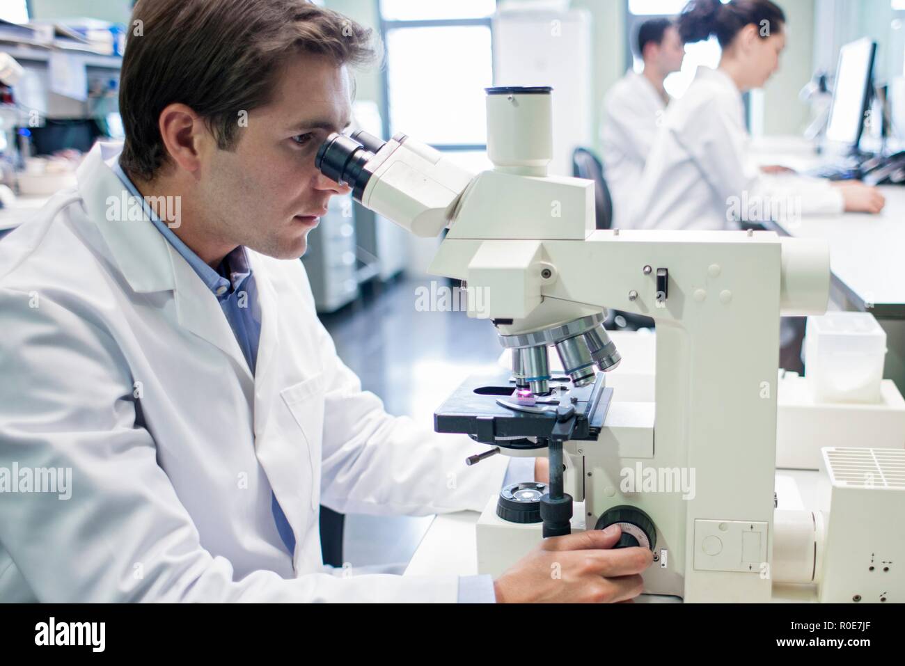 Male laboratory assistant using microscope. Stock Photo