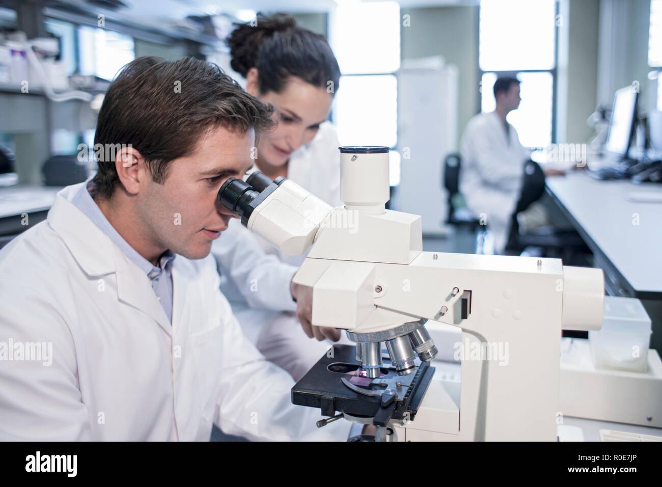 Laboratory assistants using microscope. Stock Photo