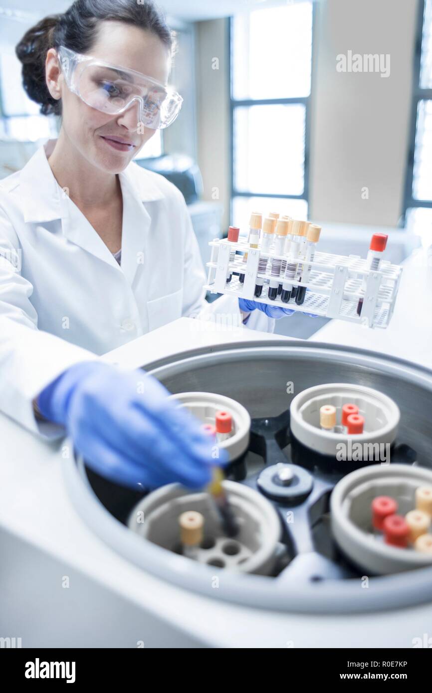 Female laboratory assistant using centrifuge machine. Stock Photo