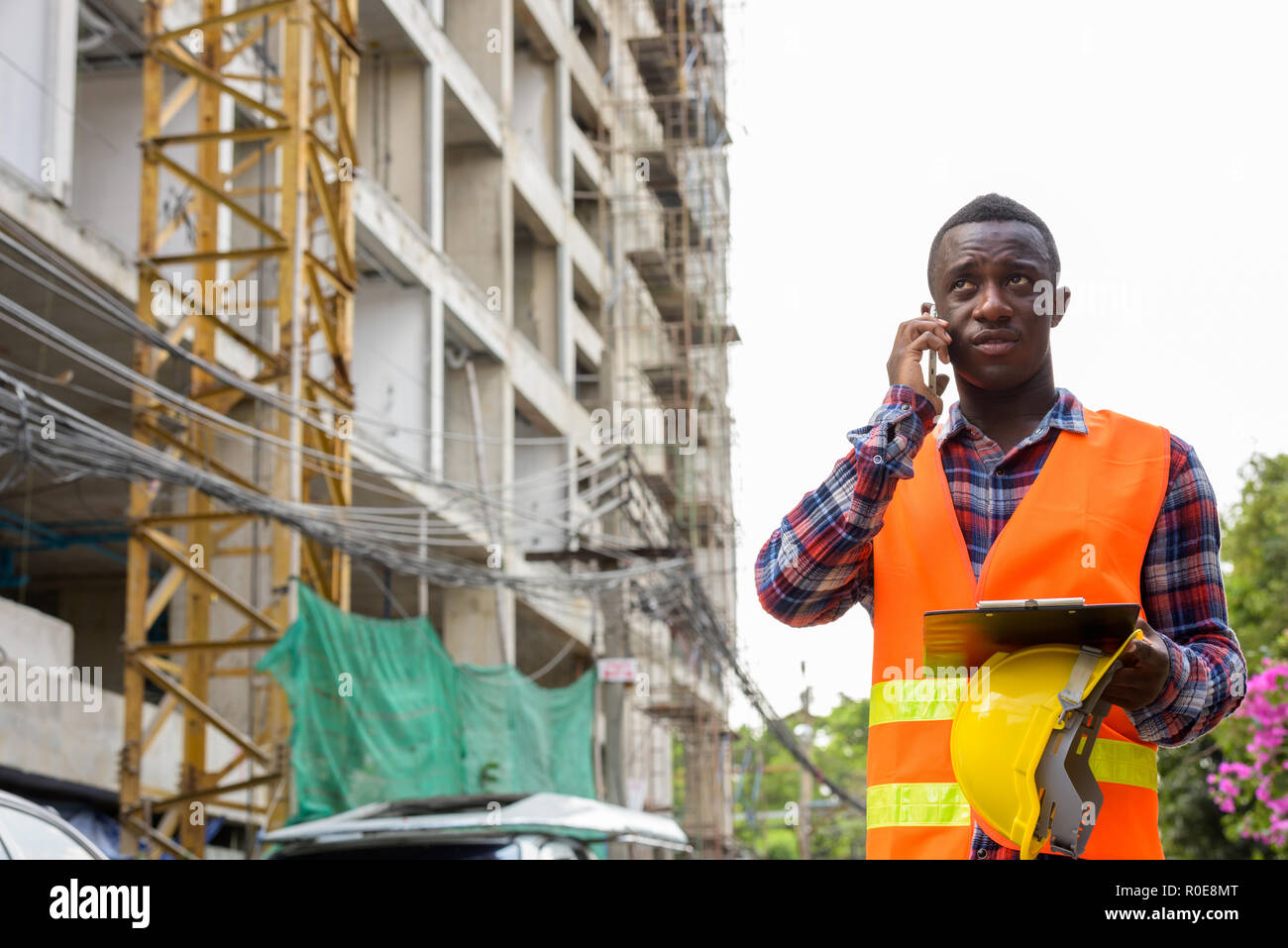 Thoughtful young black African man construction worker talking o Stock Photo