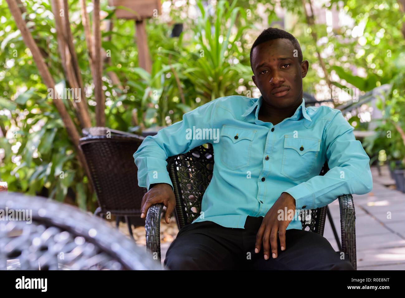 Young black African man sitting at outdoor coffee shop surrounde Stock Photo