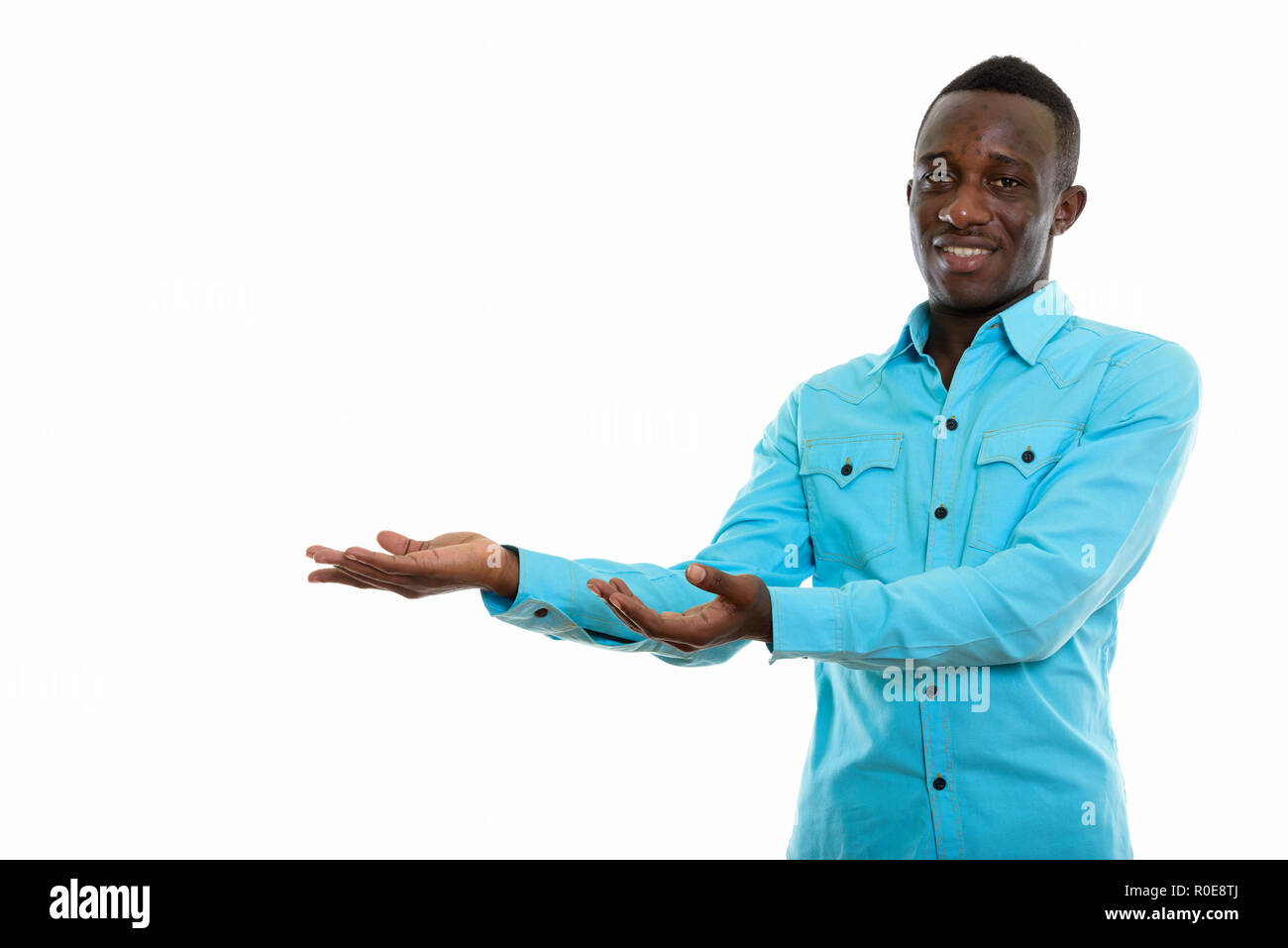Studio shot of young happy black African man smiling while showi Stock Photo