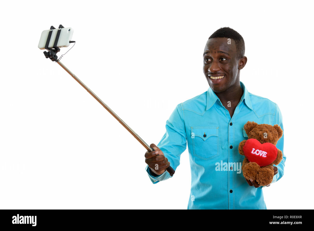 Young happy black African man smiling and holding teddy bear wit Stock Photo