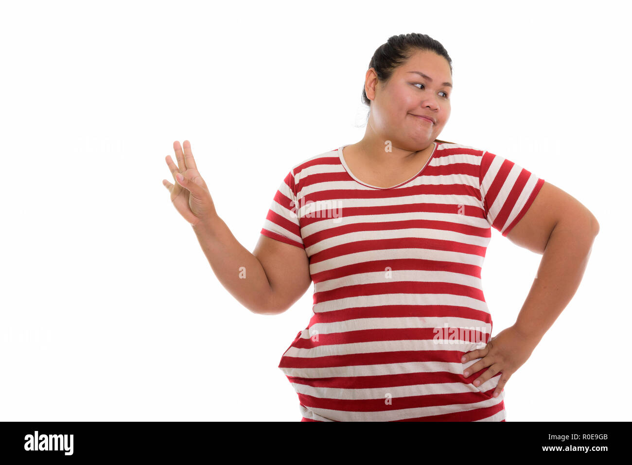 Studio shot of young fat Asian woman showing stop sign to the si Stock Photo