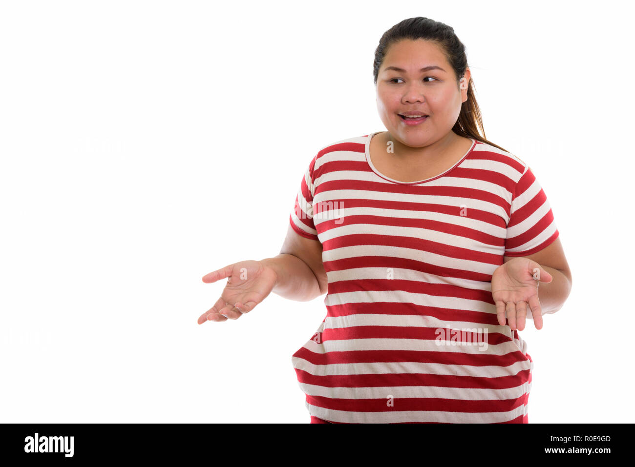 Studio shot of young fat Asian woman looking confused Stock Photo