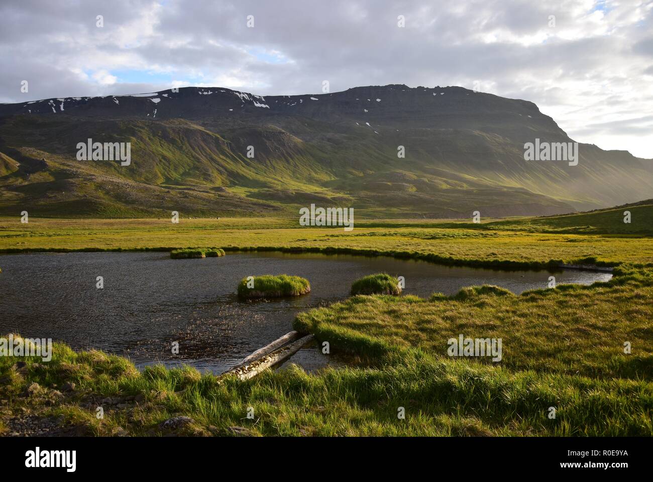 Icelandic landscape on Peninsula Skagi, at Grettislaug. A pond, grassland and a mountain in the evening sun. Stock Photo