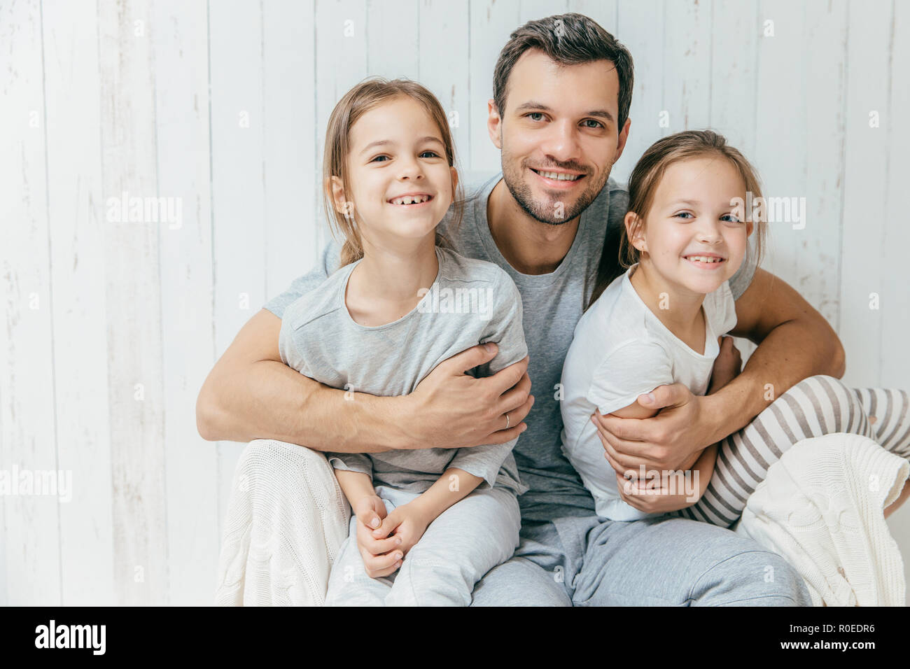 Portrait of happy young father embraces his two daughters, loves them very  much, pose together at home. Single dad with beautiful femle children have  Stock Photo - Alamy