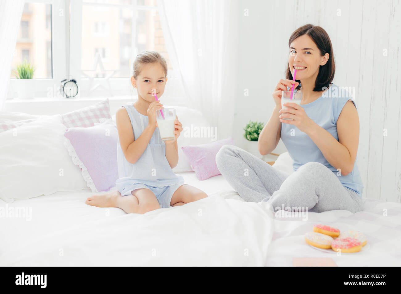 Cheerful Mother And Daughter Dressed In Pyjamas Have Breakfast In