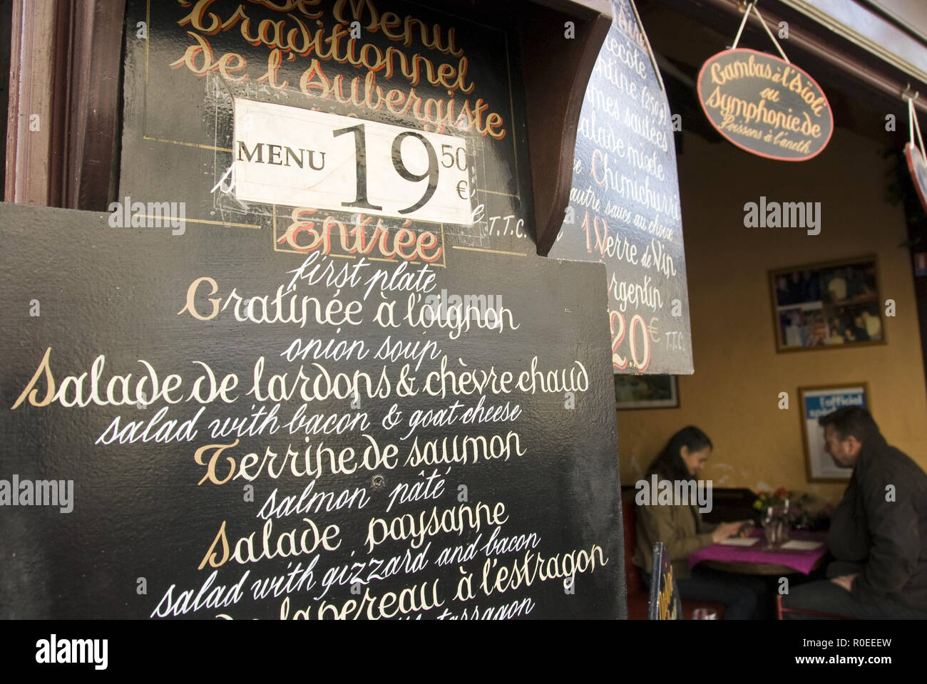 A restaurant offers a fixed-price meal (prix-fixe menu) on a sign on Rue Mouffetard, a popular street lined with cafes, bars, souvenir shops, and an o Stock Photo
