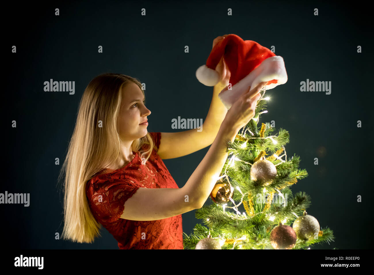 Young woman decorates the Christmas tree. Elf and spruce with decorations. Girl and adornment. Stock Photo