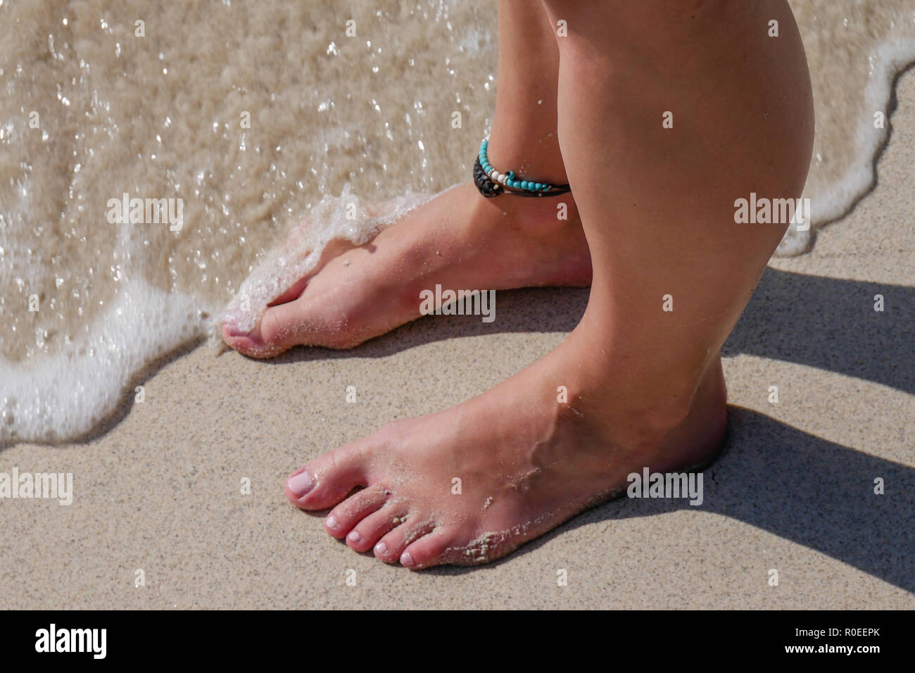 Barefooted woman on the beach waiting for the waves. Stock Photo