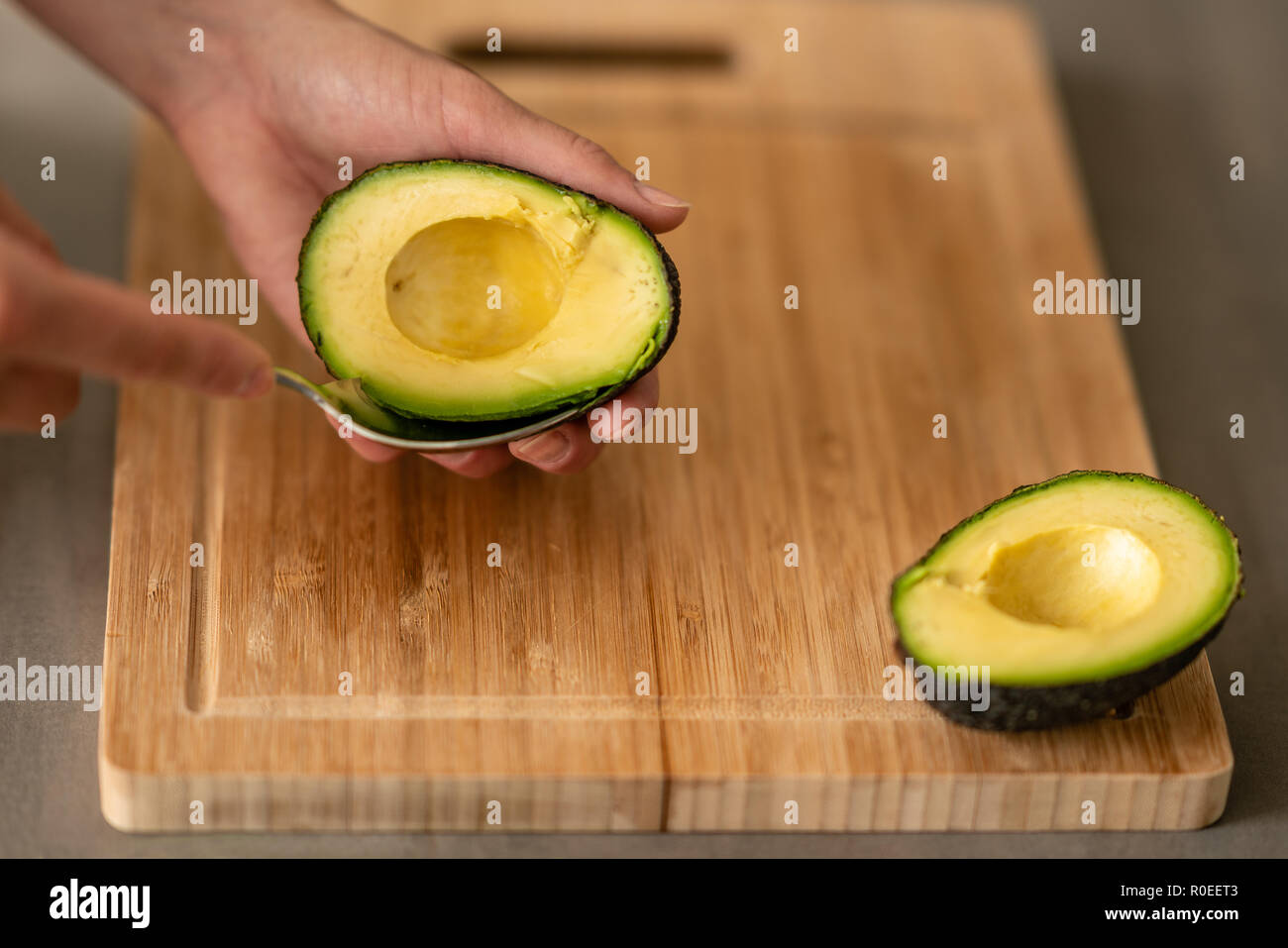 A woman hollowing out a avocado to make guacamole. Stock Photo