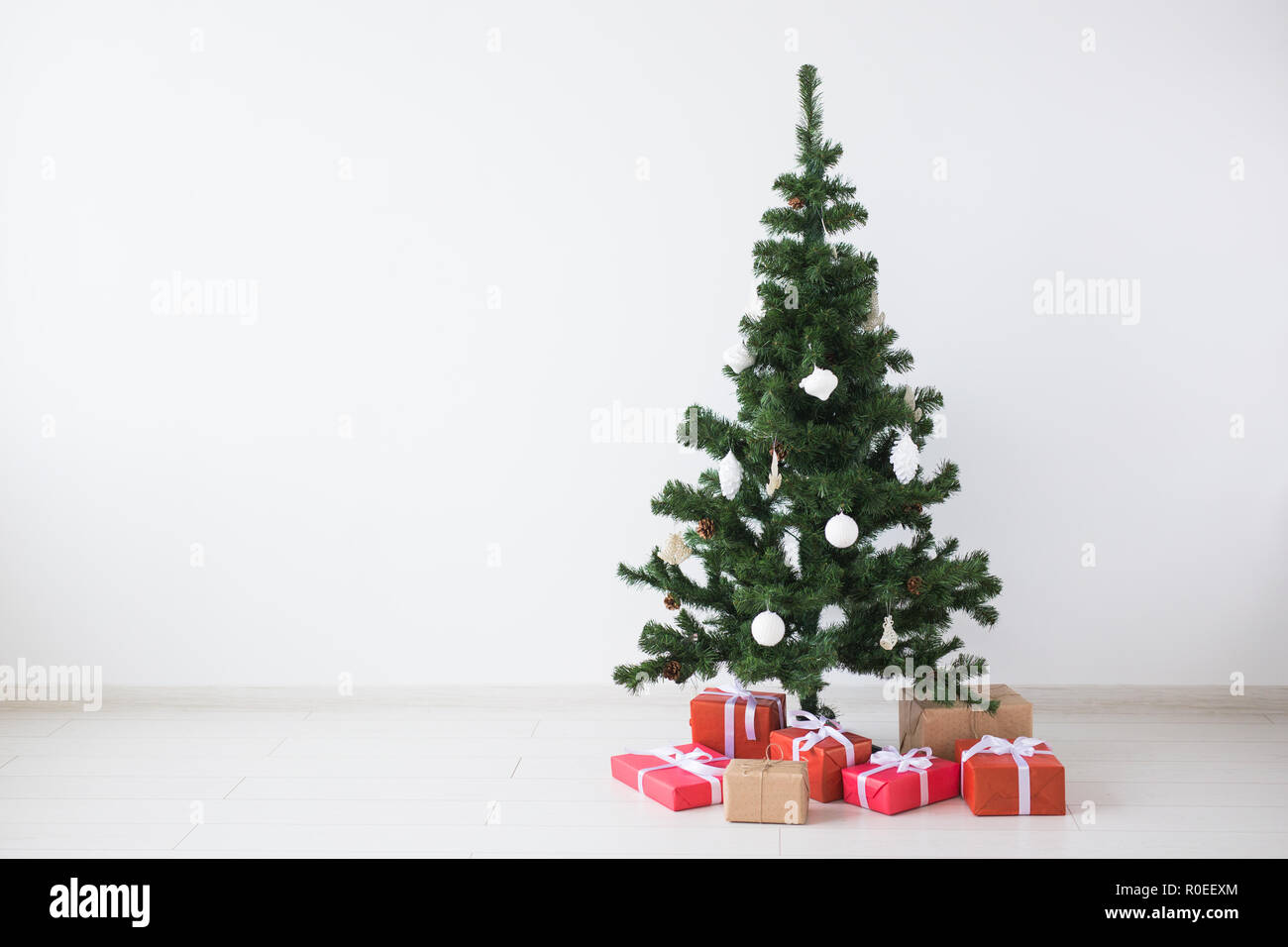 Christmas tree with balls and gift boxes over white wall with copy ...
