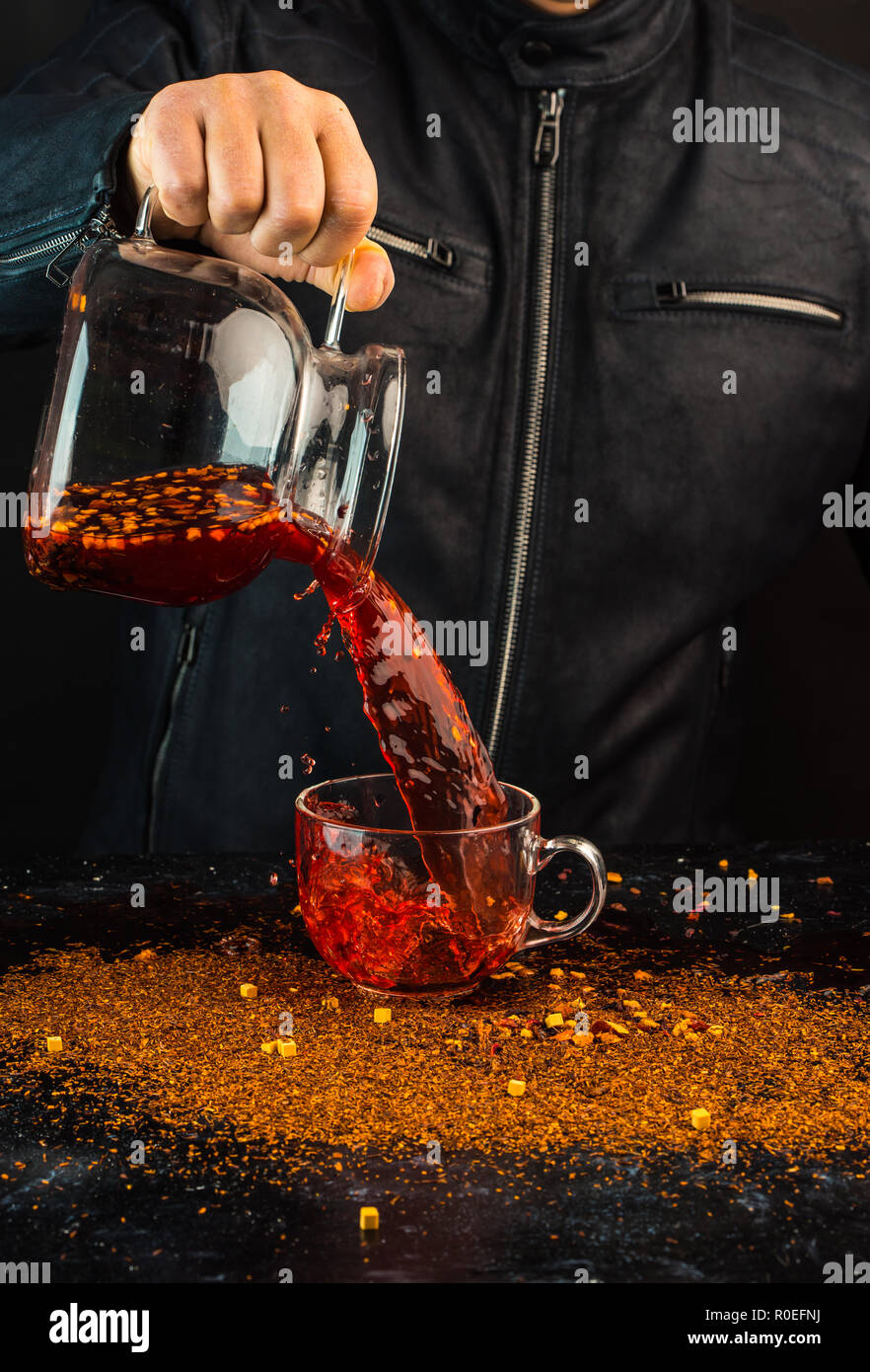 a man pours a drink from a jug into a glass cup, you can see drops and a liquid splash Stock Photo