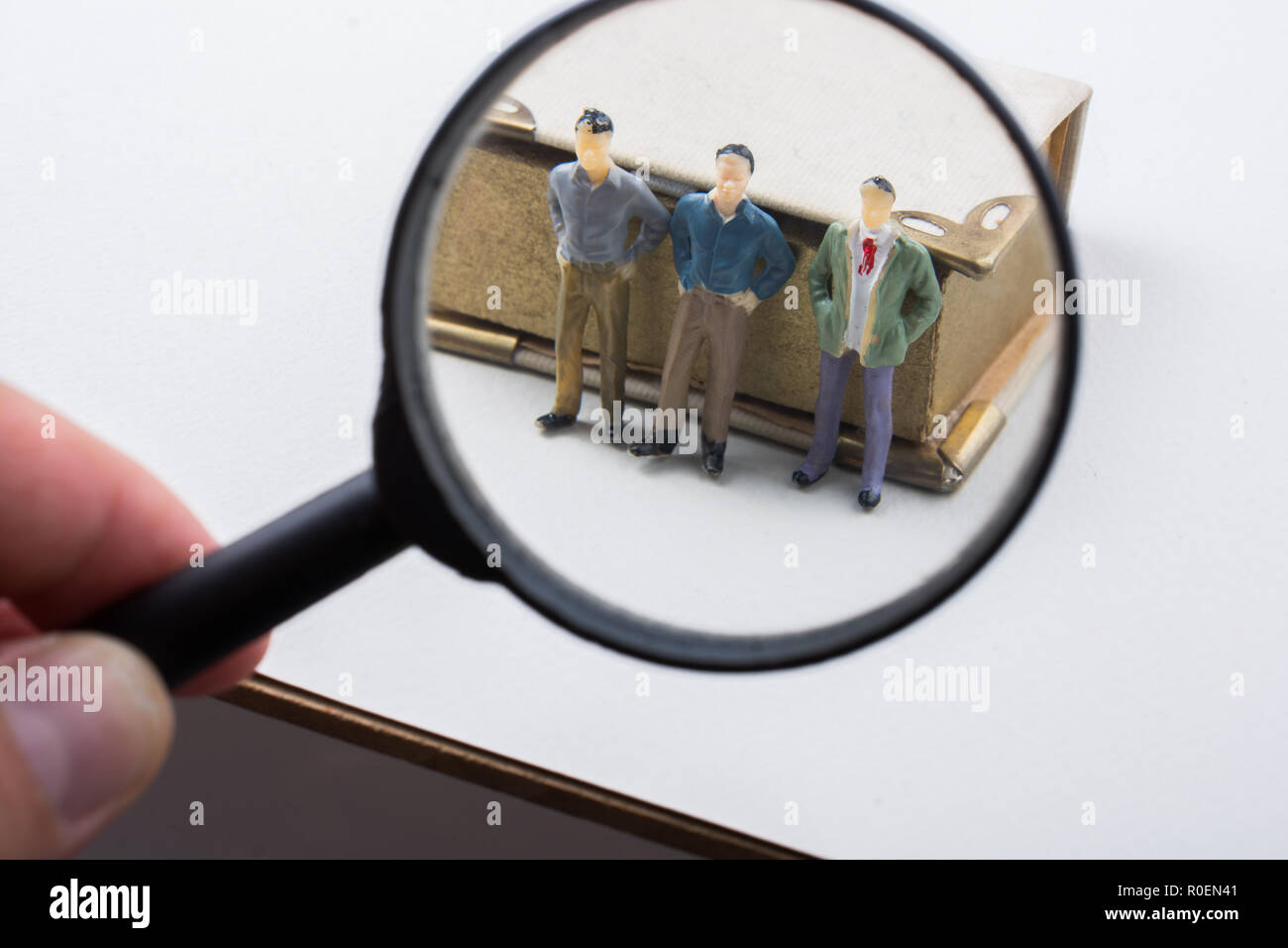 Tiny of men beside a book under magnifying glass Stock Photo - Alamy