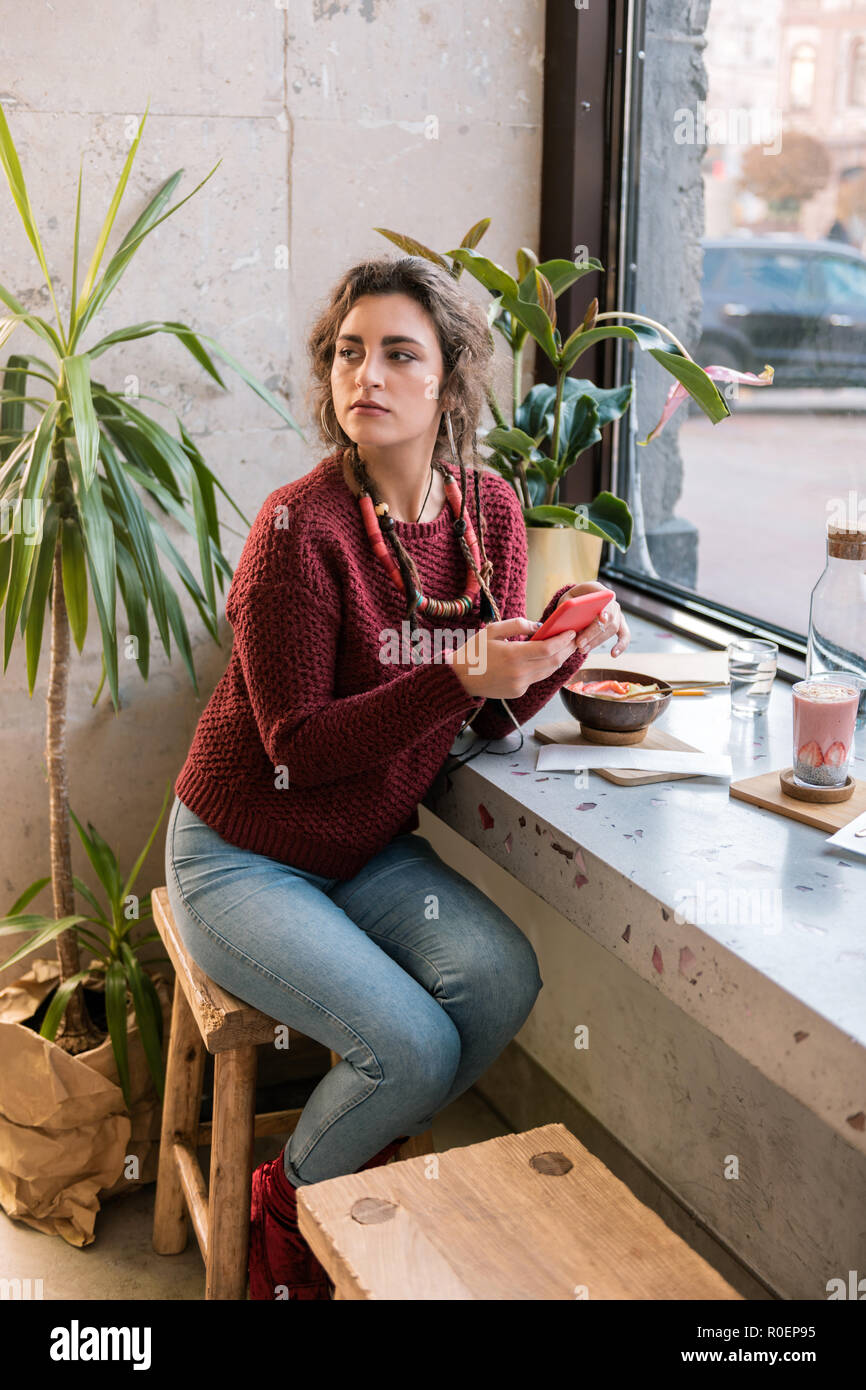 Woman wearing dark red sweater waiting for boyfriend in cafeteria Stock Photo