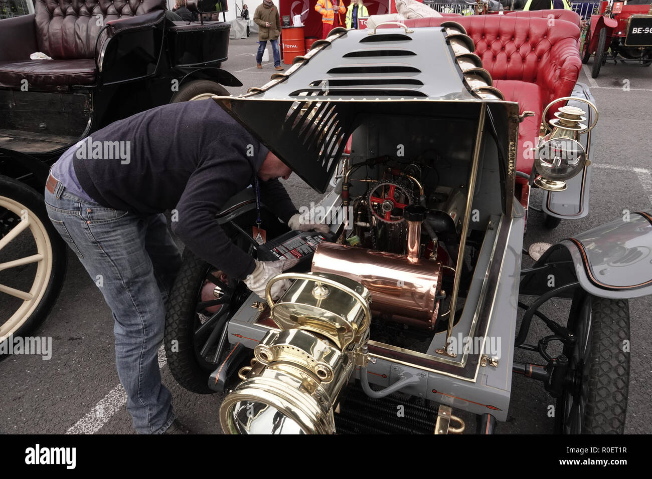 Crawley, West Sussex, UK. 4th November, 2018  Crawley, West Sussex,  UK  Veteran automobile entusist tinkers with his car at the halfway stage cars stopped at the Honda garage in Crawley on the Bonhams sponsored London to Brighton Veteran car run halfway stop at the Honda showroom in Crawley, Credit: Motofoto/Alamy Live News Stock Photo