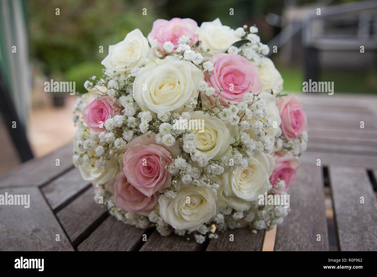 brides-wedding-day-bouquet-of-pink-and-cream-roses-sitting-on-a-table-outside-in-daylight-R0F962.jpg