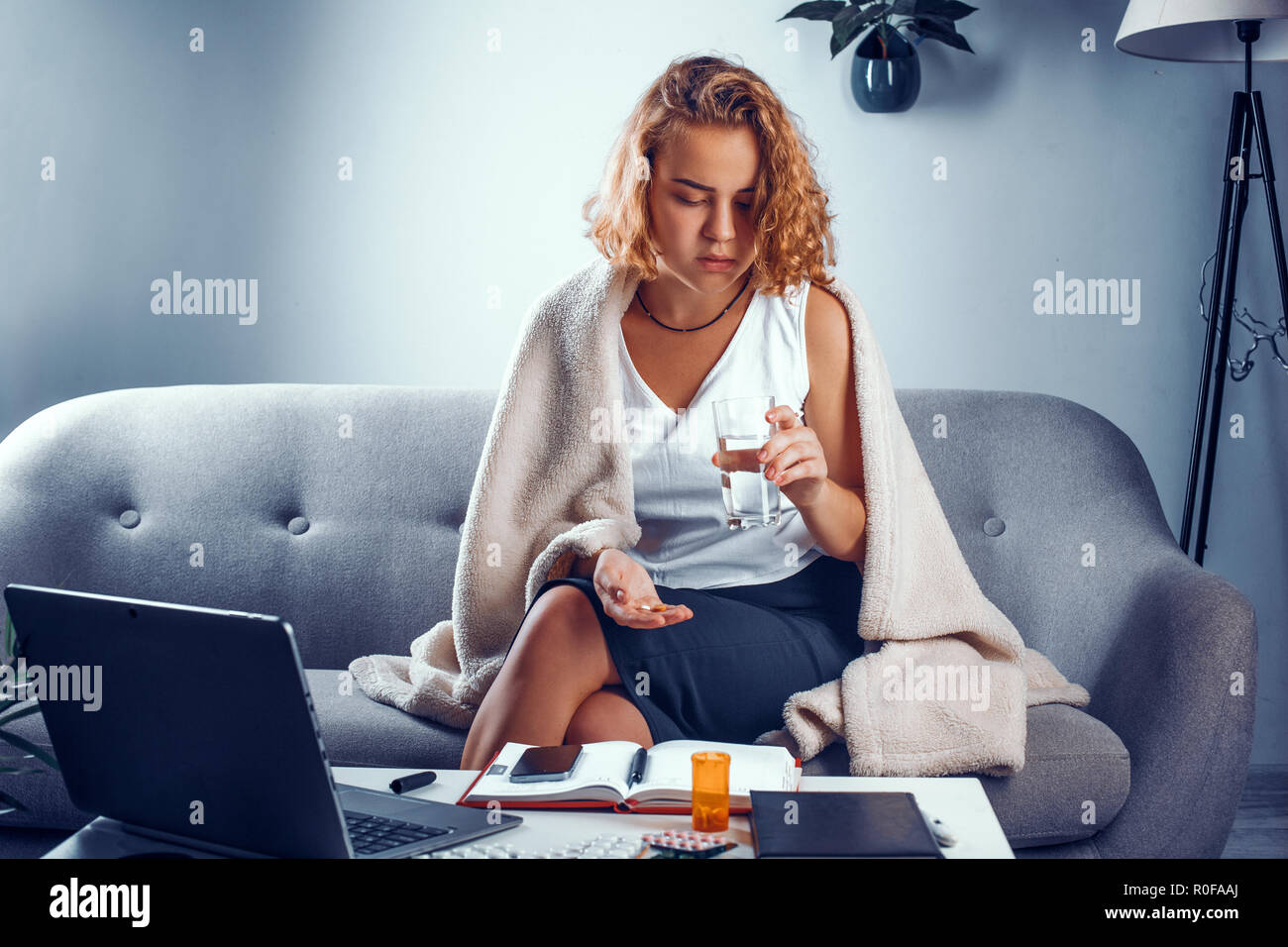 Young woman looks at the glass of water and pills. Stock Photo