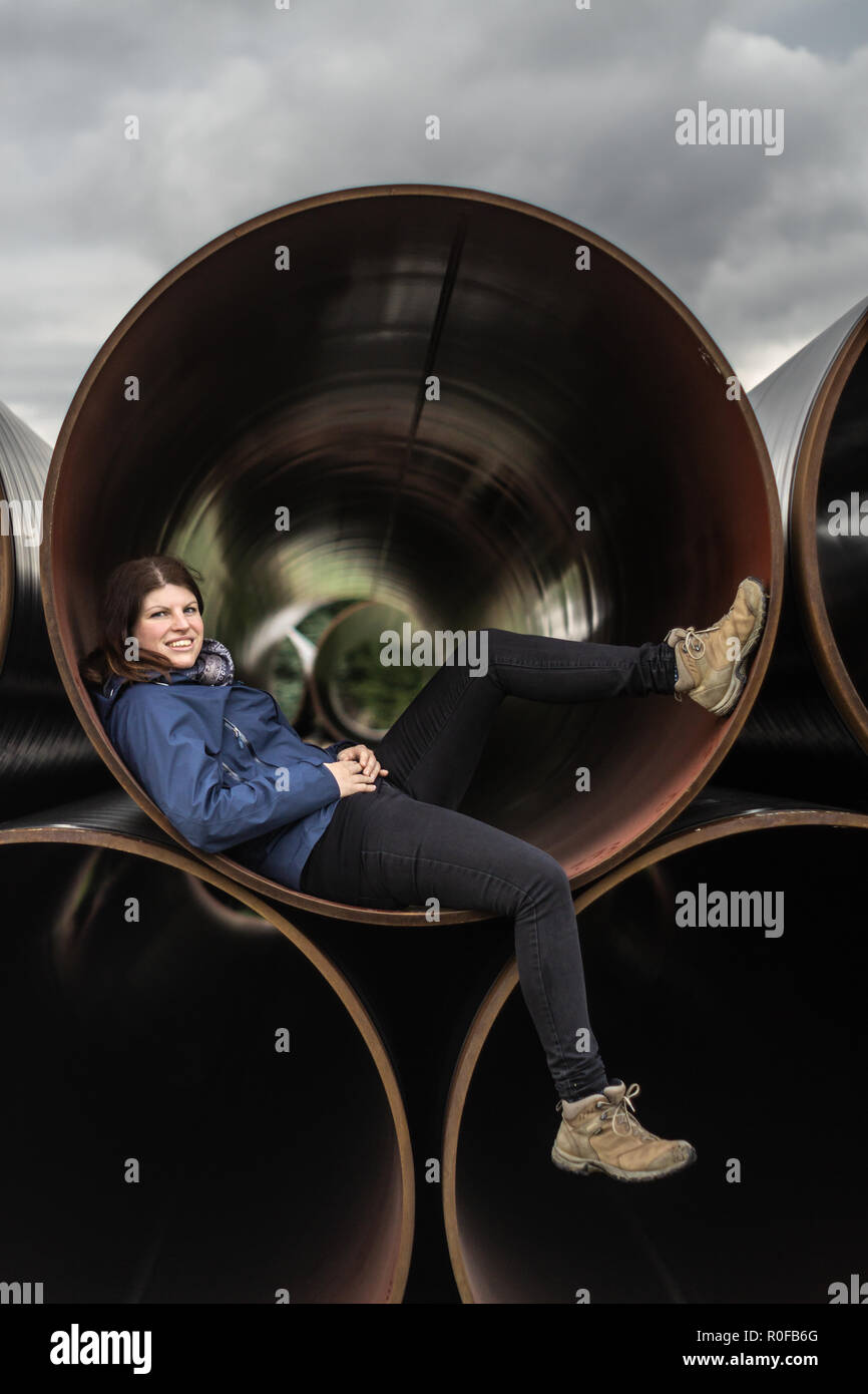 Woman chills in Stacked Oil pipes on a field Stock Photo