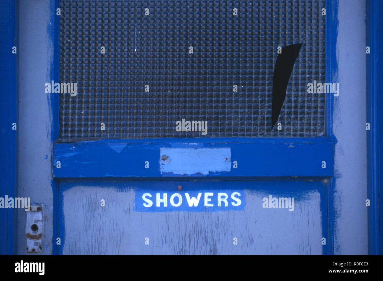 Run-down door with the word ' Showers' and broken glass Stock Photo