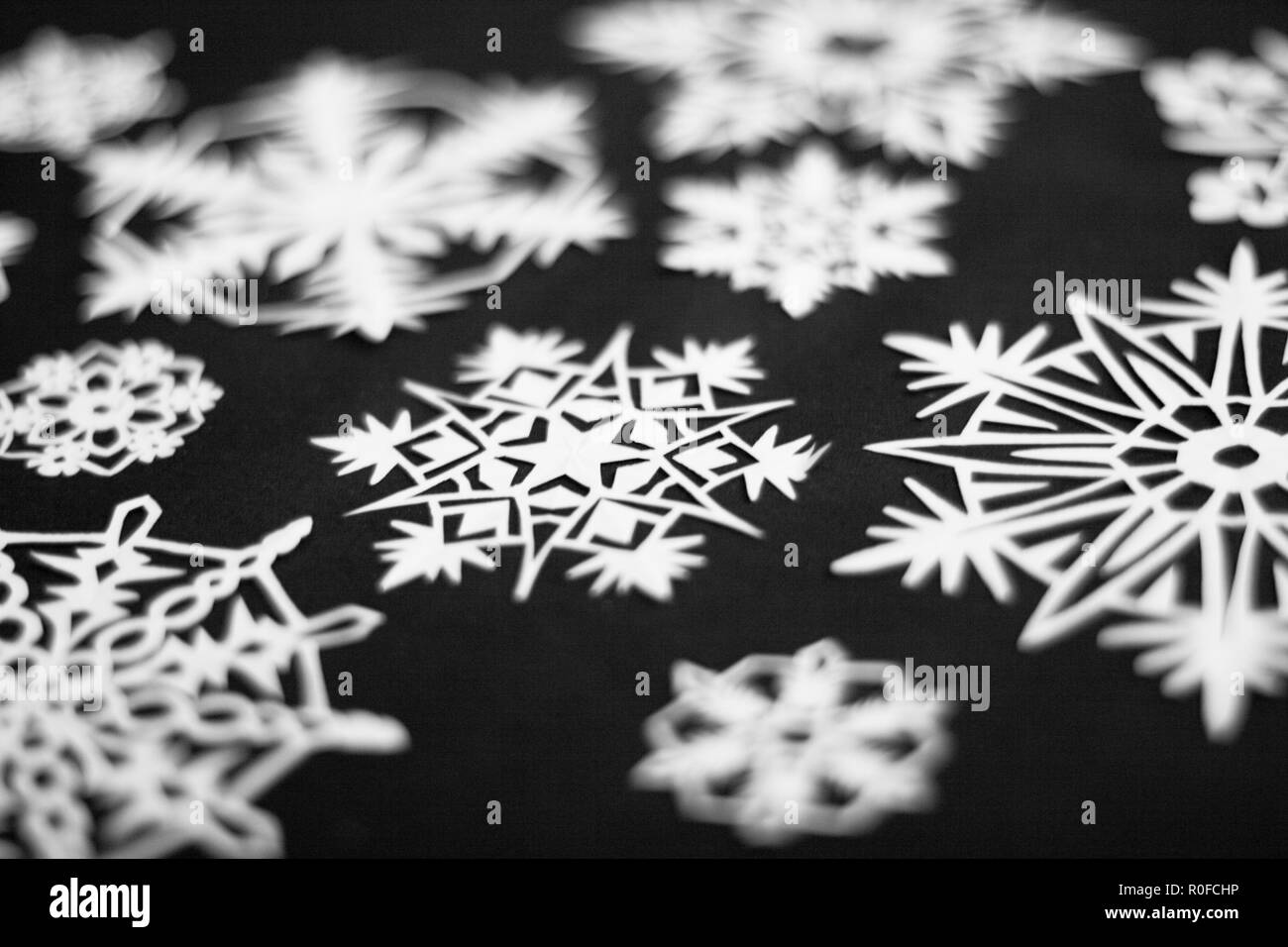 a lot of paper white cutout snowflakes on black background Stock Photo ...